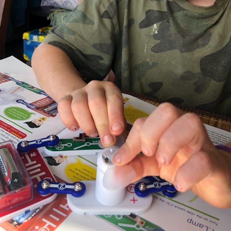A child's hands assembling a snap-together electronics circuit